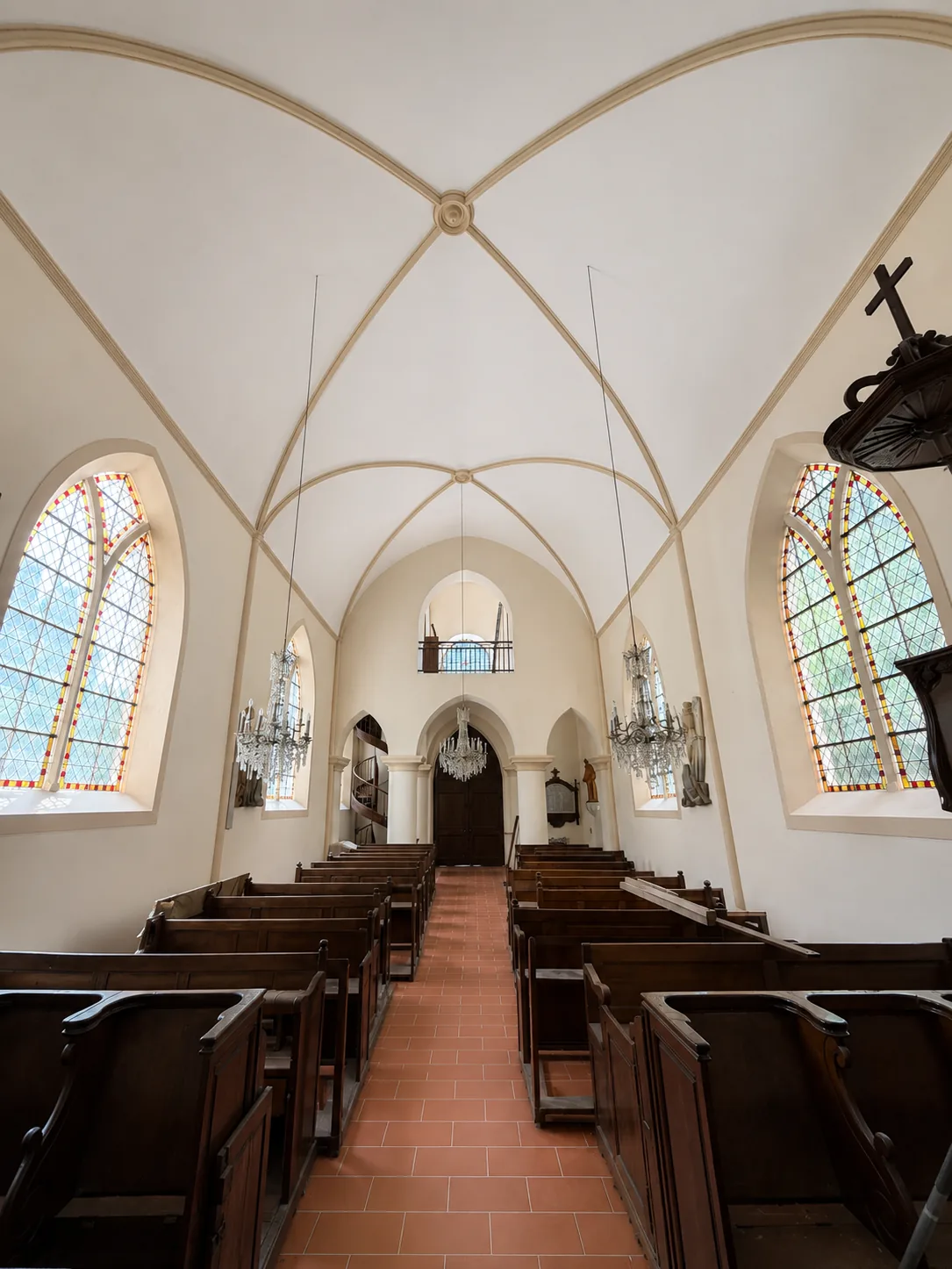 Intérieur voûté clair avec vitraux et mobilier en bois
